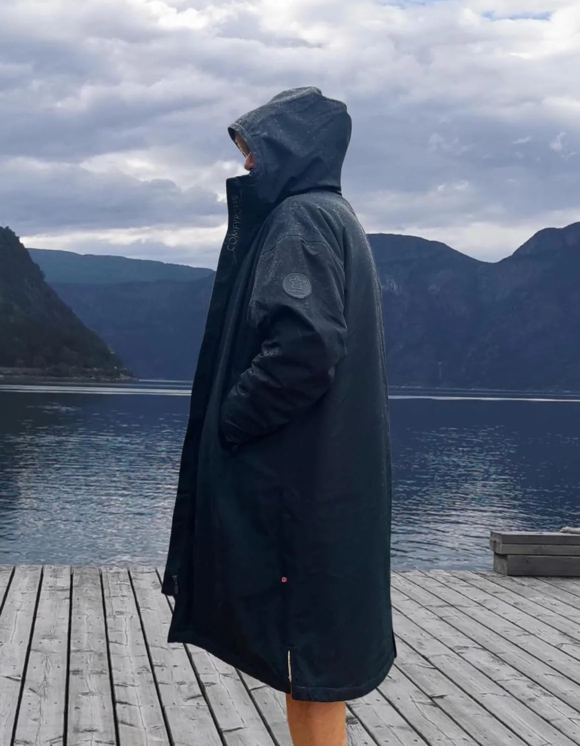 Comfyrobe som tåler regnvær, vist i et norsk kystlandskap.