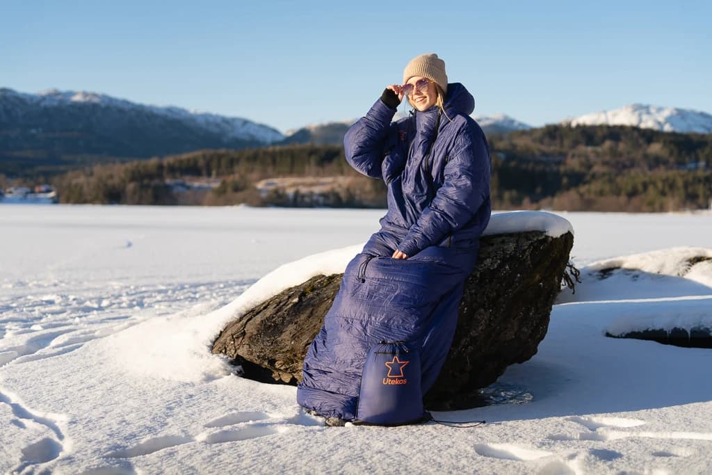 To personer i Utekos-plagg nyter utsikten fra en fjelltopp.